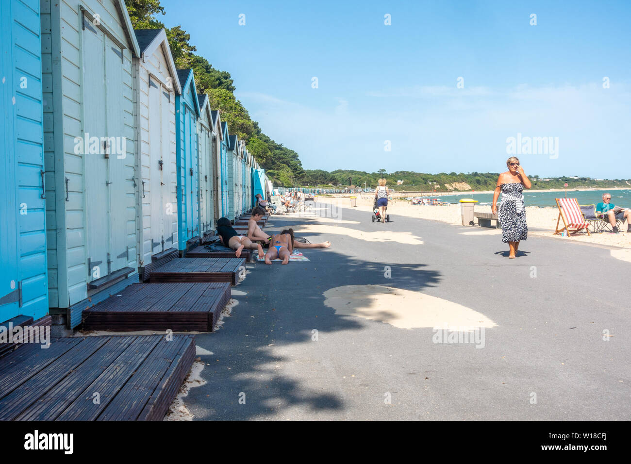 Row of beach huts in different pastel blue shades run along the top of Avon Beach at Mudeford, Christchurch in Dorset, UK. A sandy beach with pebbles. Stock Photo