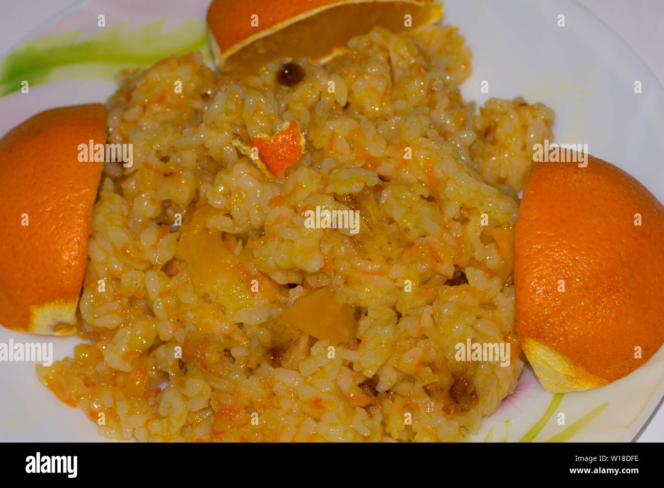 Lean pilaf with peppers and barberries on a plate decorated with oranges Stock Photo