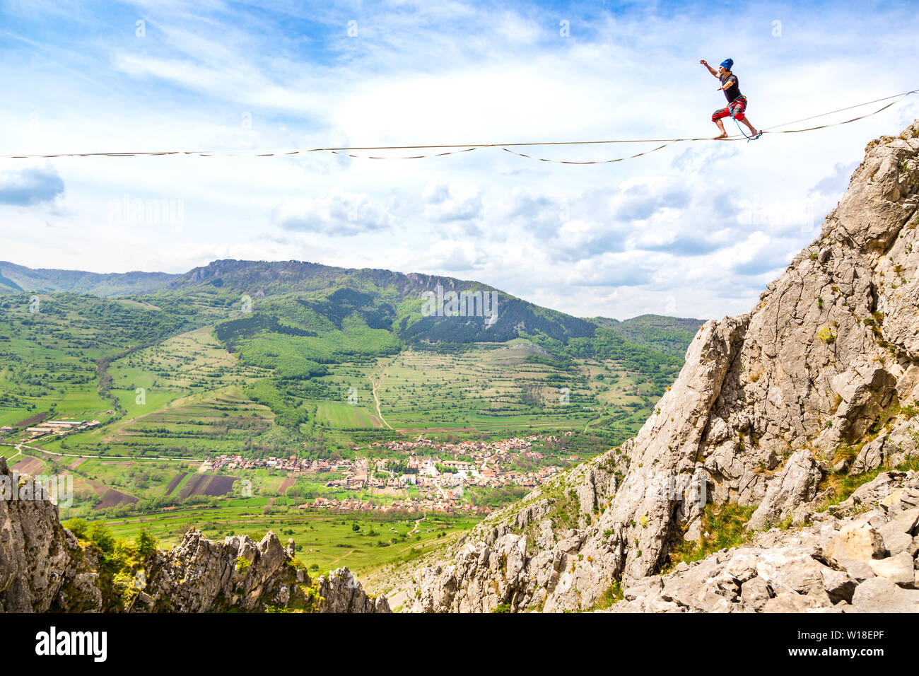 Young man on a highline above sharp jagged cliffs. Slackline in the