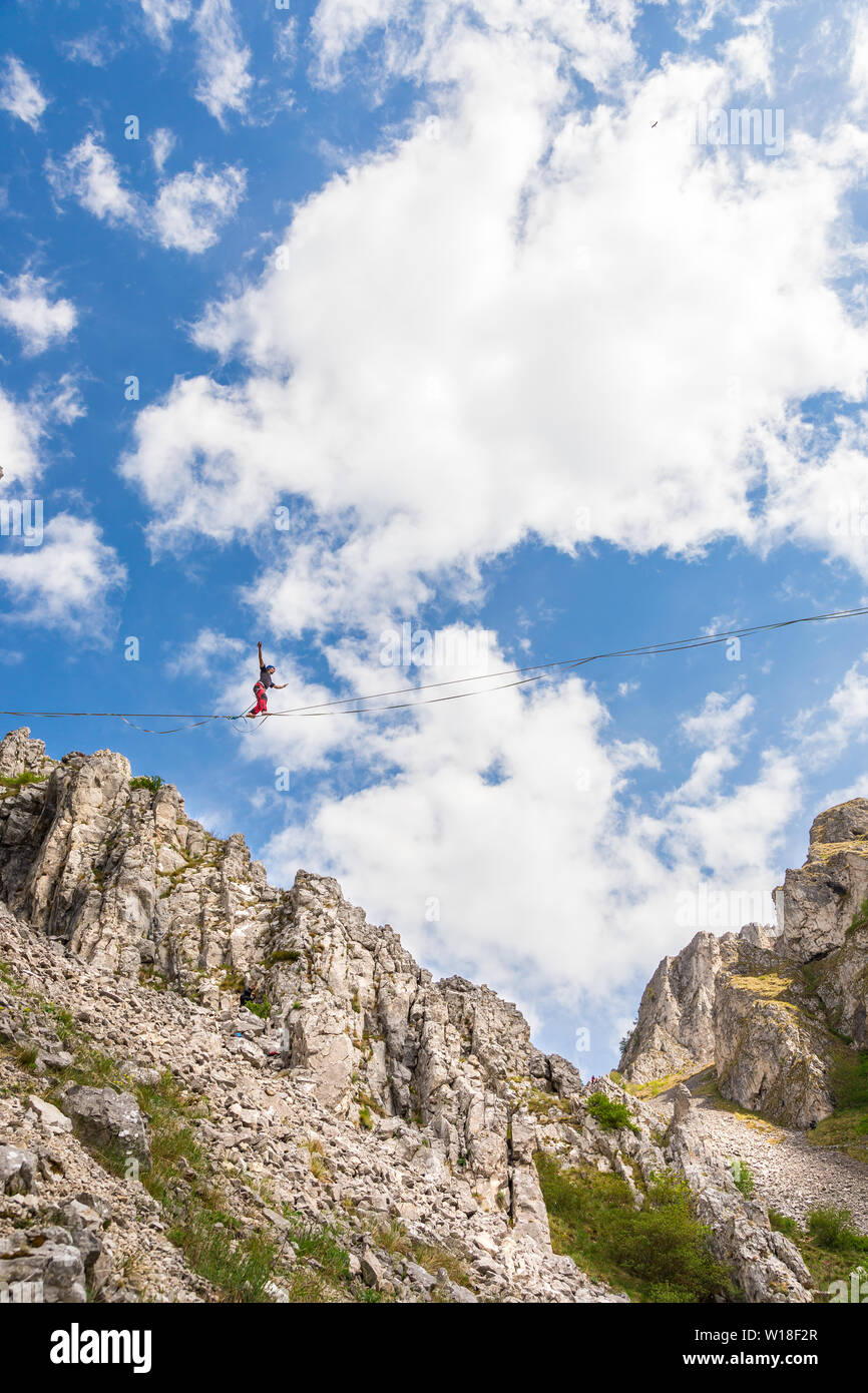 Young athlete walking on a slackline tight rope betweend two rocks