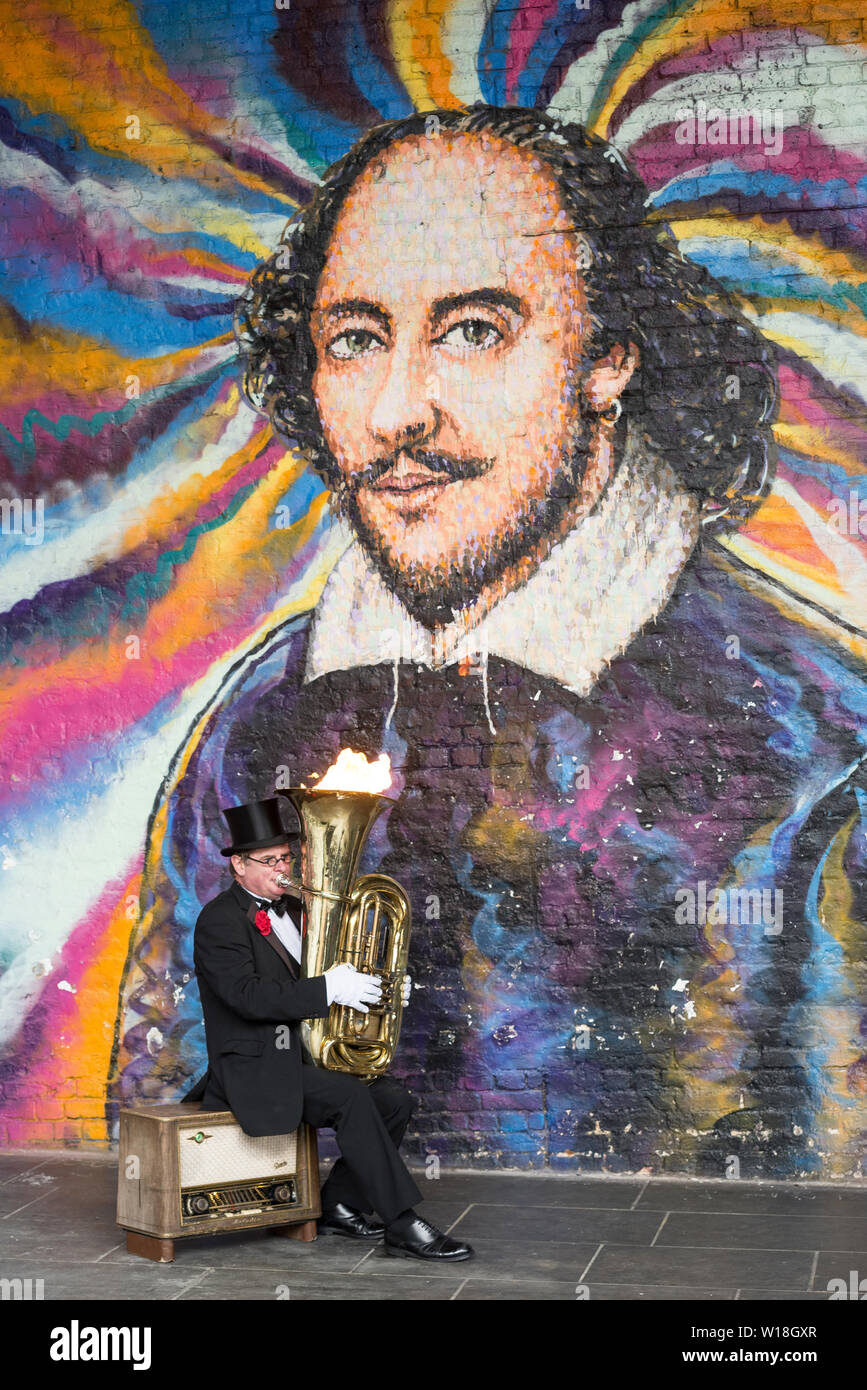 Street performer in front of William Shakespear street art on the South Bank of London Stock Photo