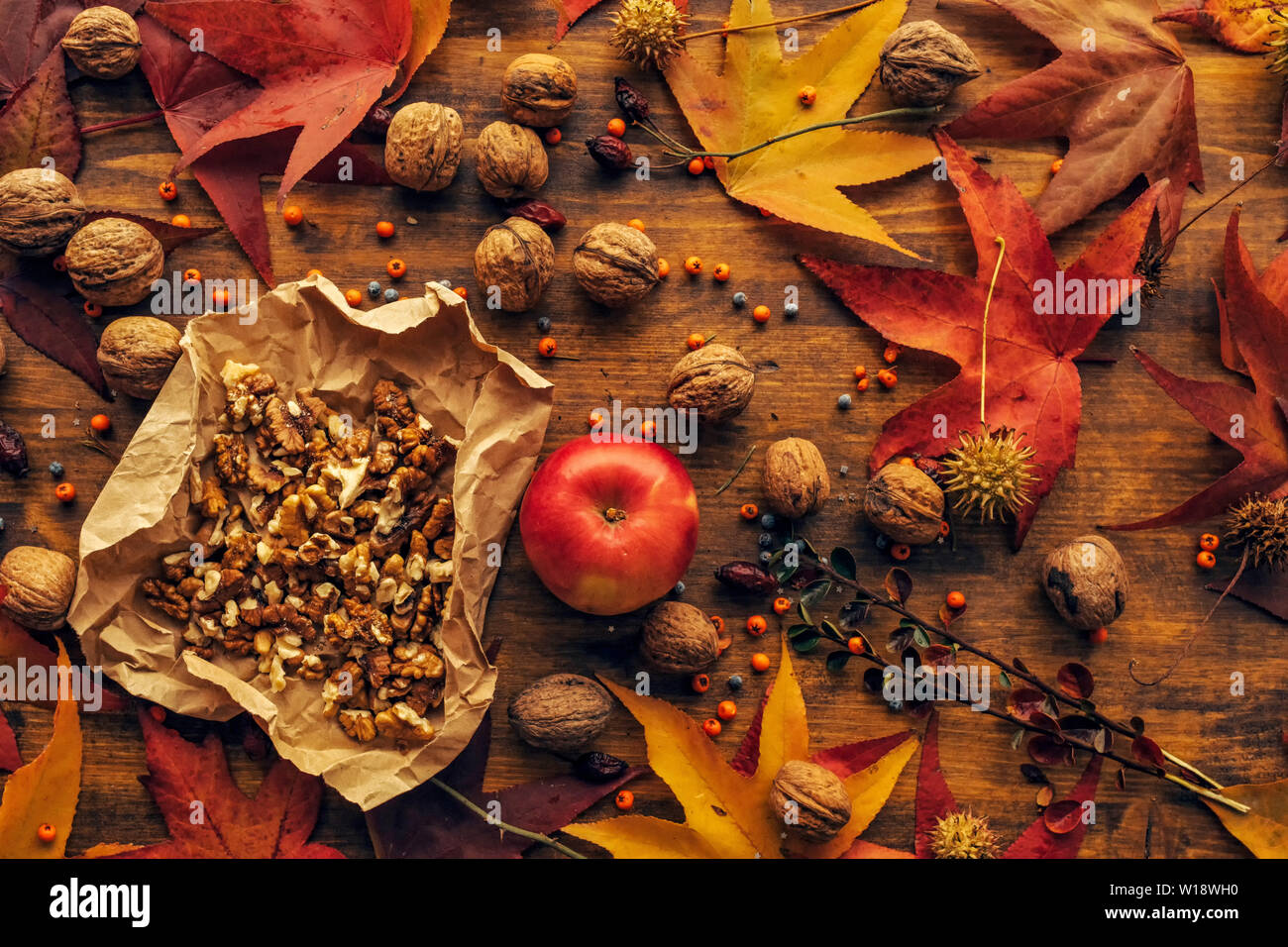 Apple and walnut, autumn abundance - healthy organic fruit on wooden table decorated with colorful maple leaves and berries, top view Stock Photo