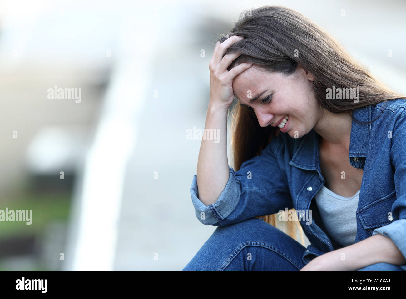 Sad girl crying alone sitting in the street Stock Photo