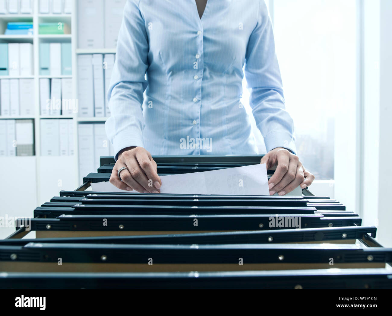 A woman filing documents into a hires stock photography and