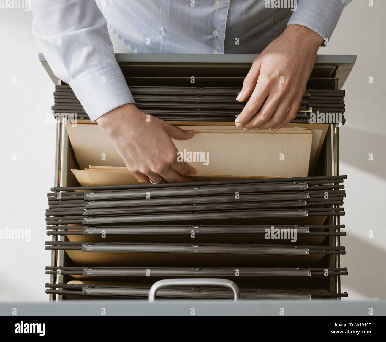 Female office worker searching files and paperwork in the archive, she