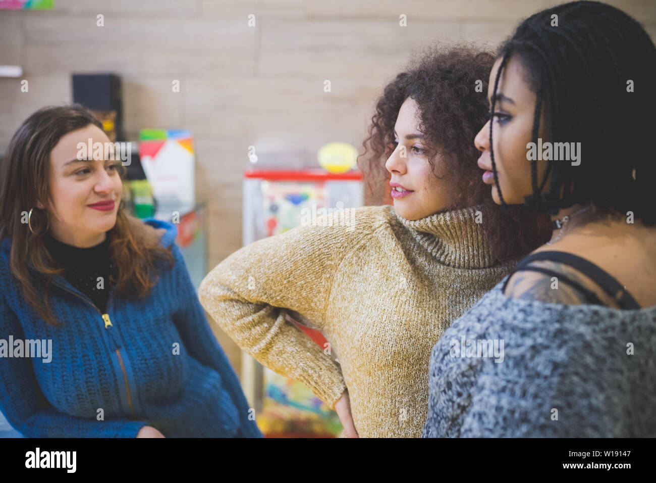 three young girlfriends having talk and looking ahead – communication, relation, interracial Stock Photo