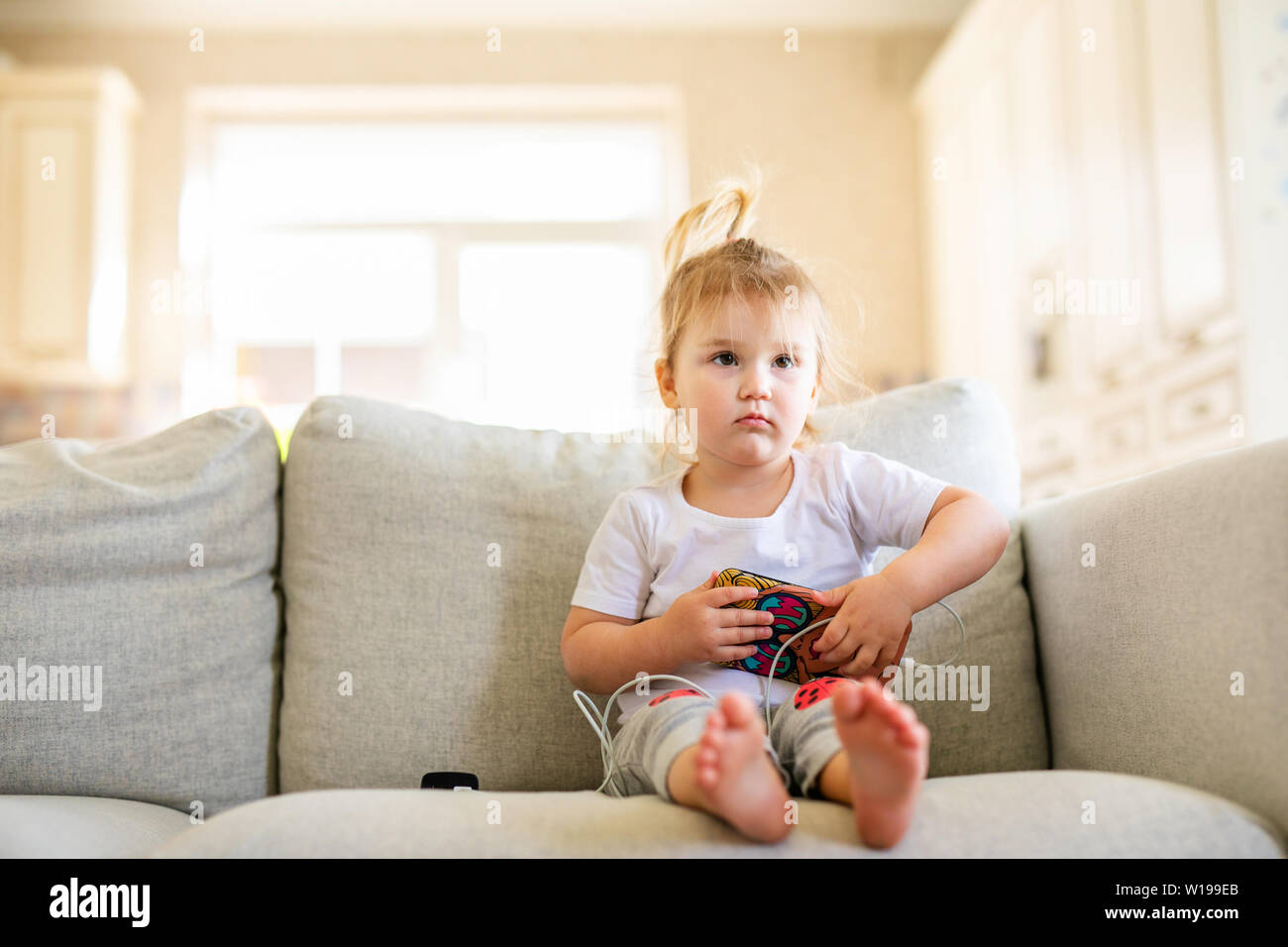 Cute little baby playing digital tablet sitting on the sofa. Parenting ...