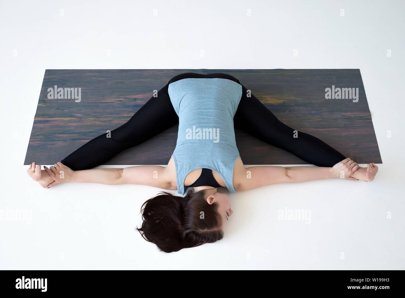 Caucasian woman doing yoga splits upavistha konasana on fitness mat. Stock Photo