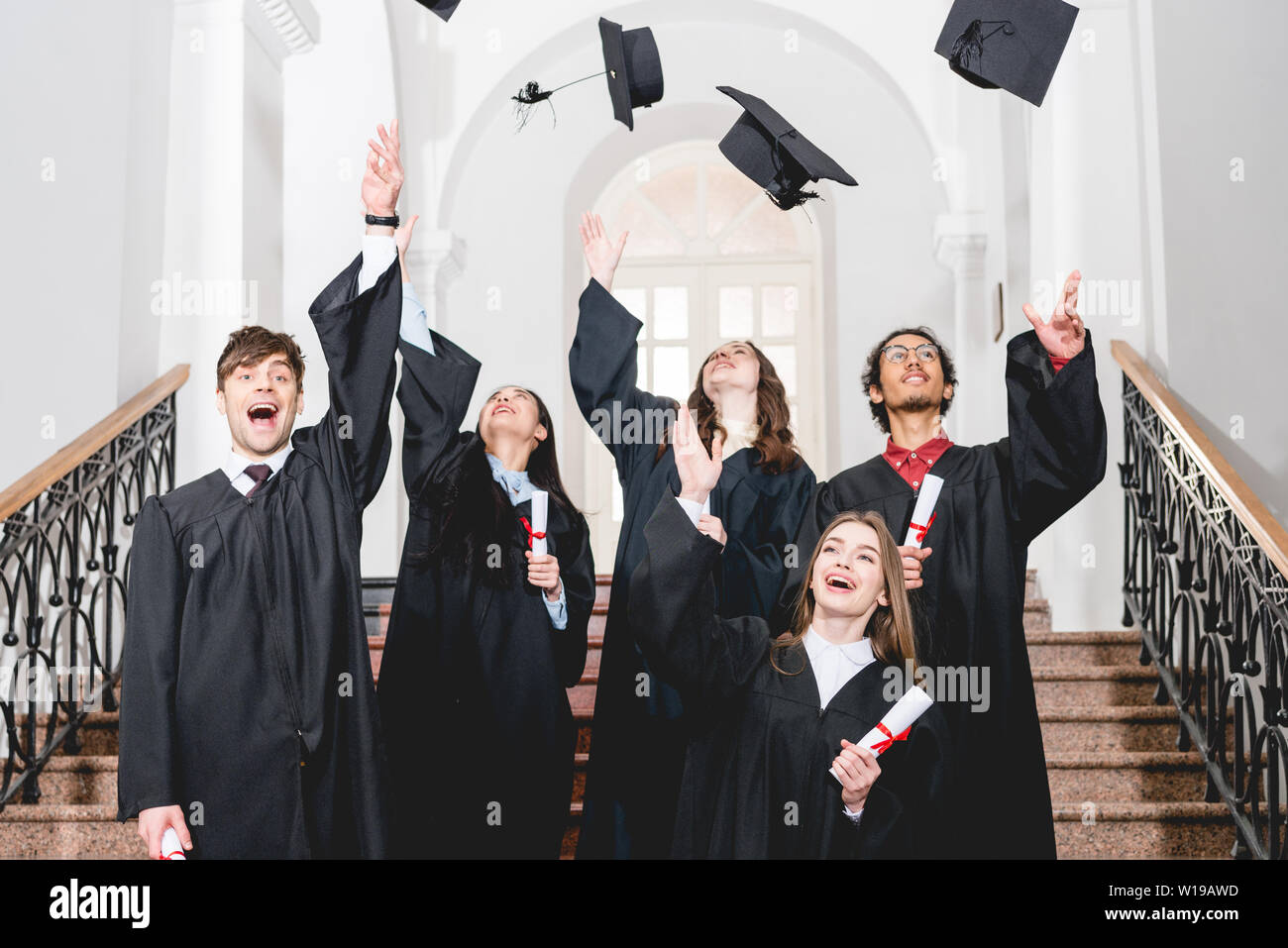 happy students smiling while throwing in air graduation caps Stock ...