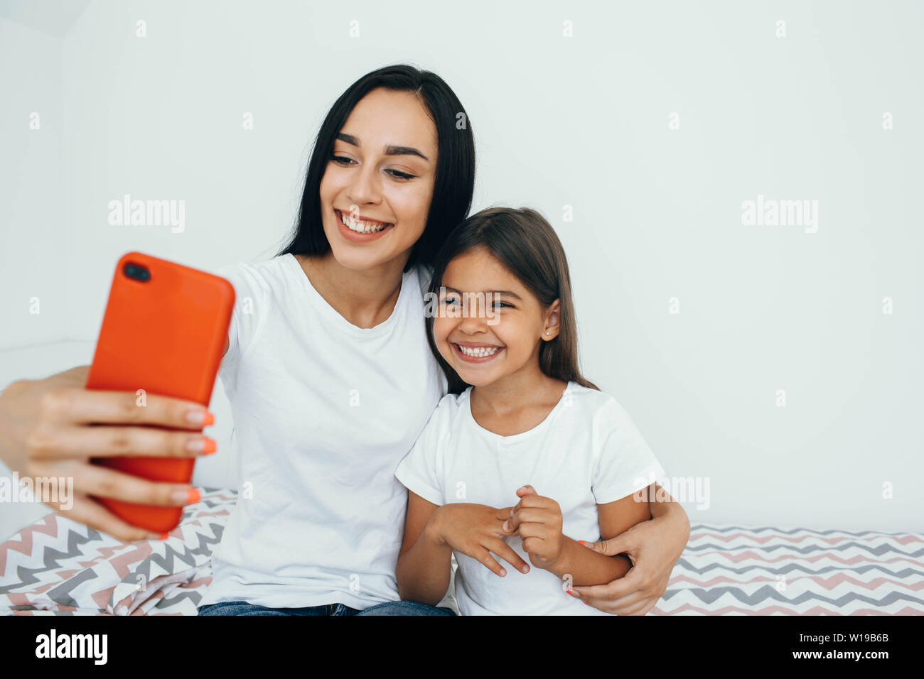 Mother and daughter funny spending time at home. Making selfie on phone Stock Photo