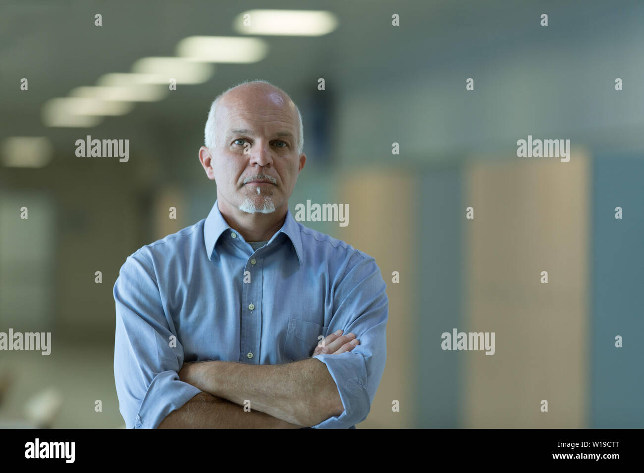 Half body portrait of senior businessman with folded arms and thoughtful expression. Stock Photo