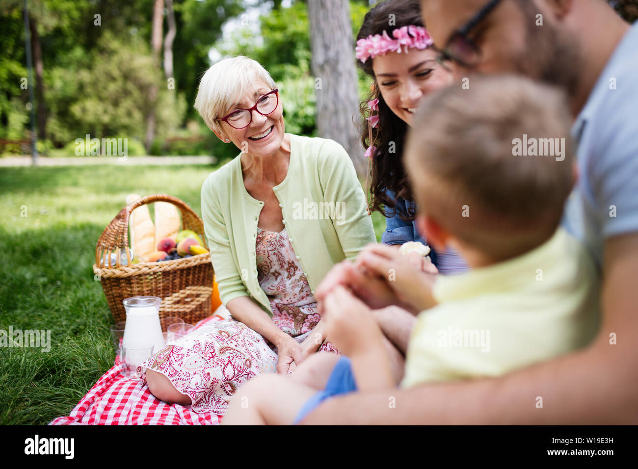 Happy young family playing on the grass in the park and enjoying picnic Stock Photo