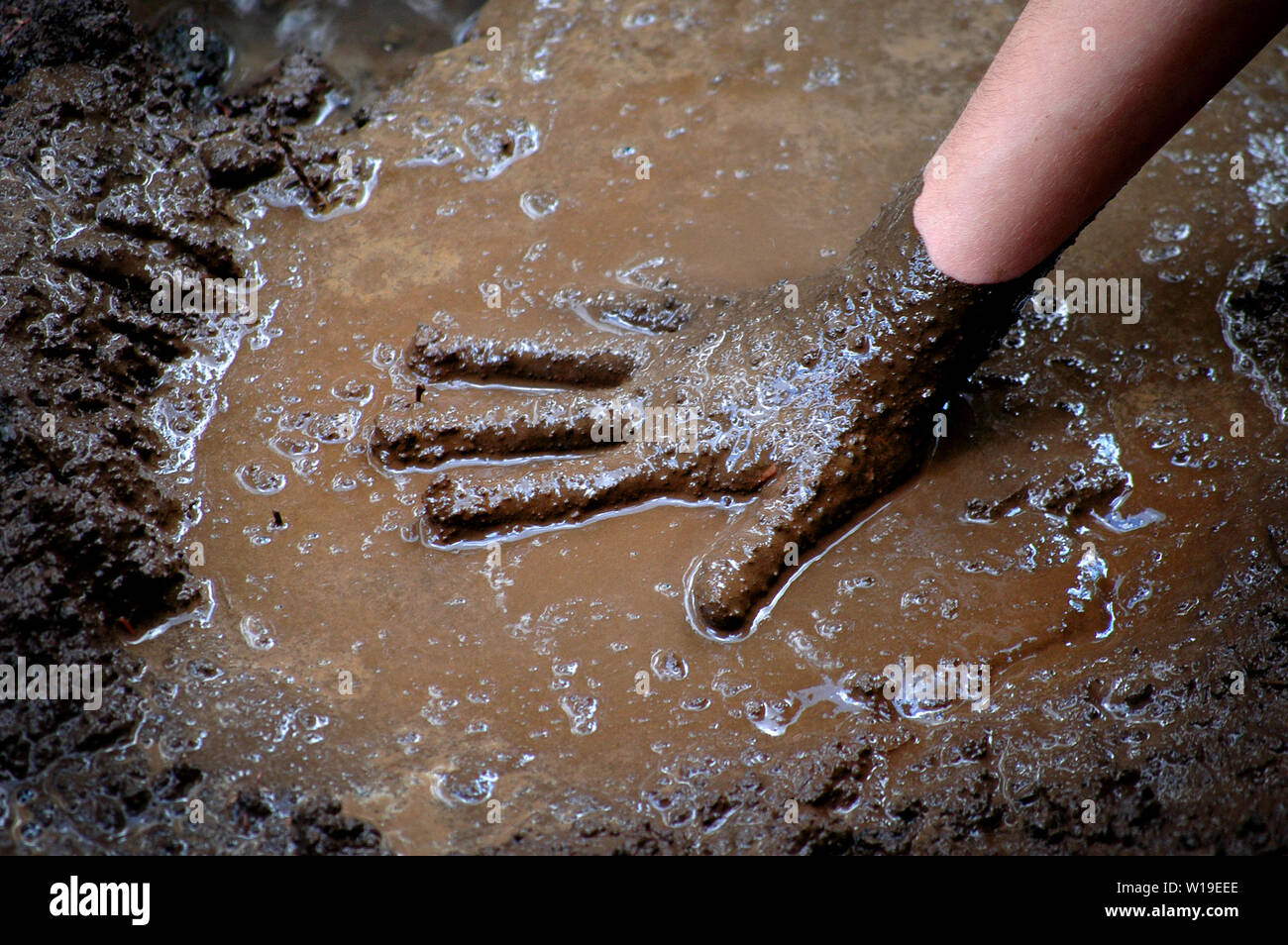 Child with hand in mud and water playing muddy games wet Stock Photo