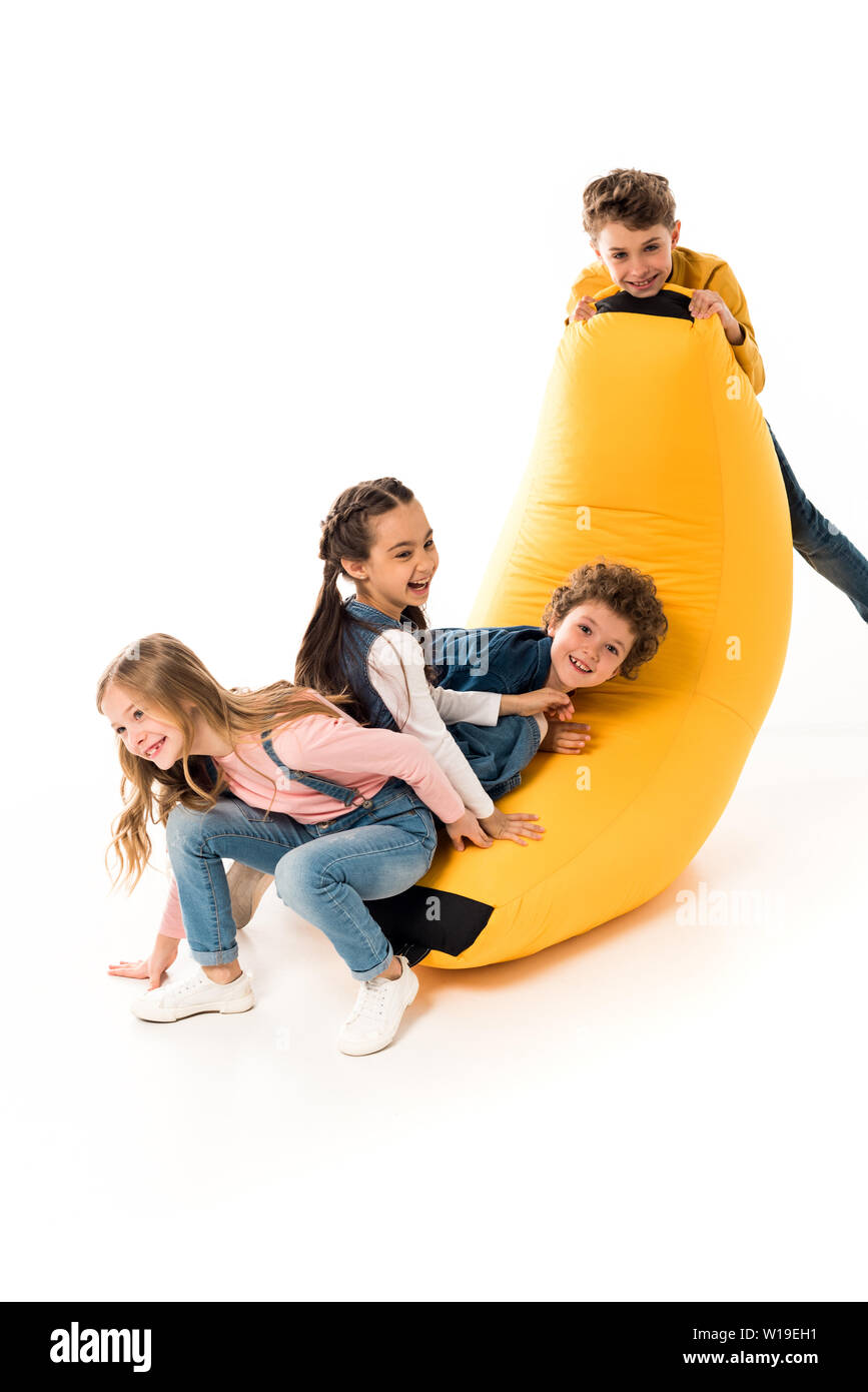 four smiling kids playing with bean bag chair on white Stock Photo Alamy