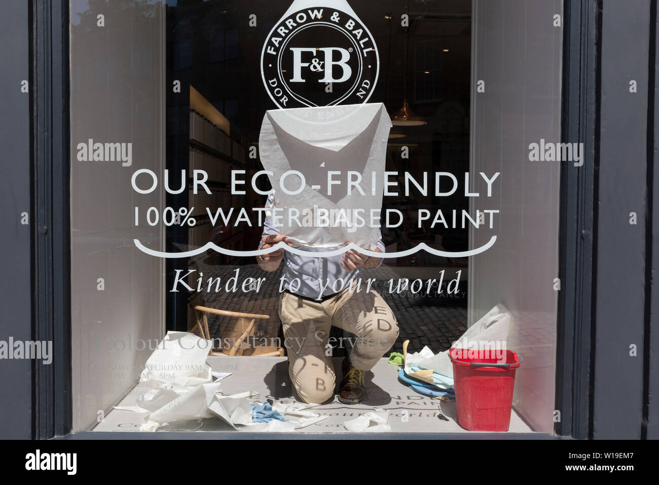 Unpeeling and sticking a window stencil to the glass of eco paint retailer Farrow & Ball, in Edinburgh, on 26th June 2019, in Edinburgh, Scotland. Stock Photo