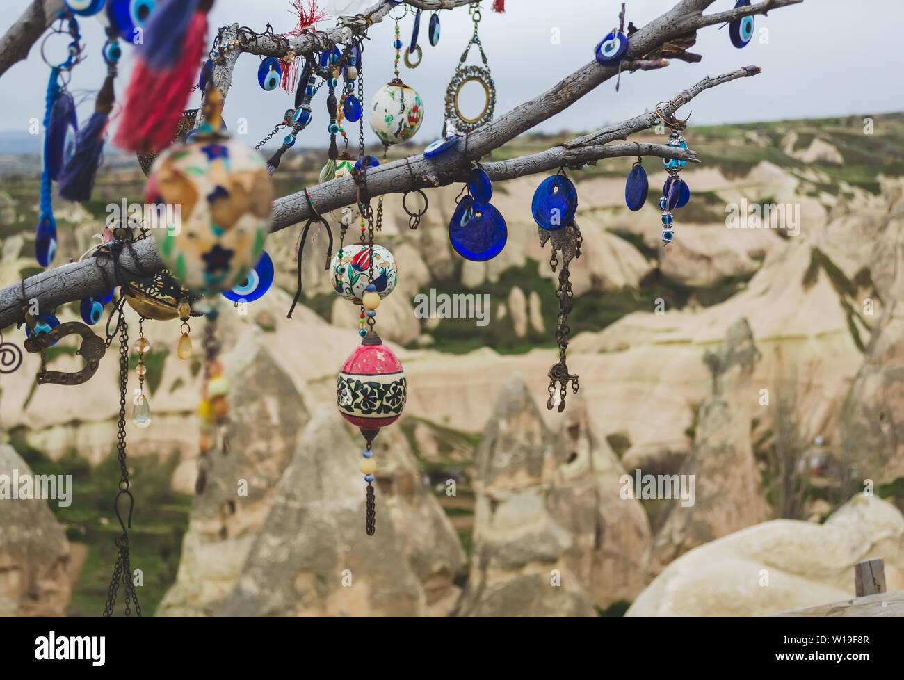 Traditional Turkish amulets and decorations hang on the branches of a wishes tree against the backdrop of the volcanic landscape of Cappadocia Stock Photo