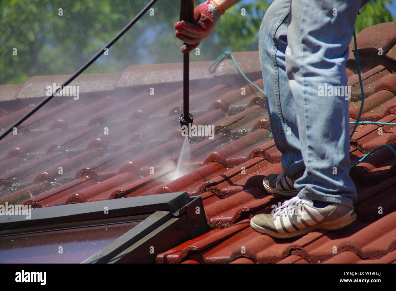 House roof cleaning with pressure tool. Moss removing with water. Tile washing with professional equipment. Stock Photo