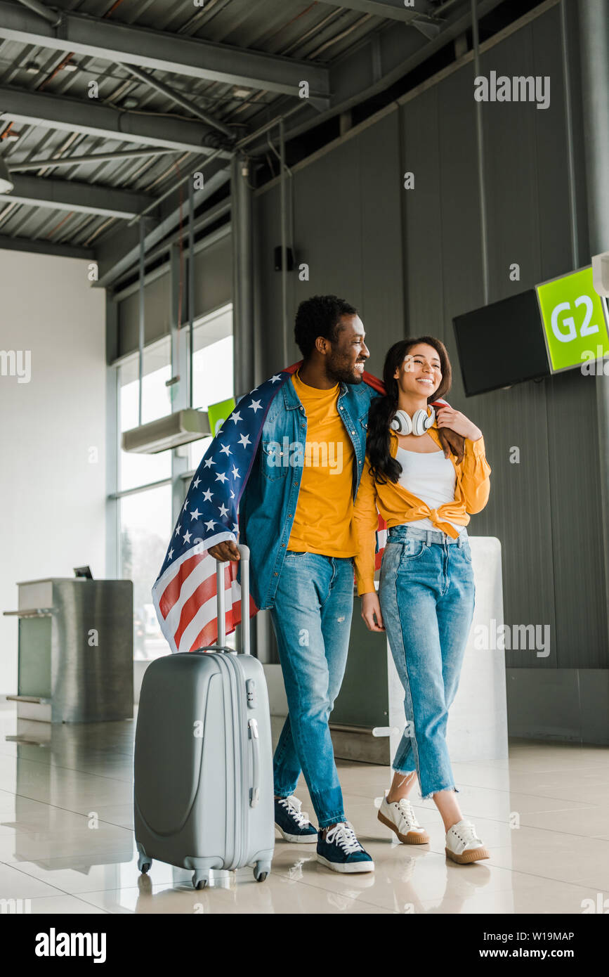 happy african american couple with - Happy African American Couple With American Flag And Suitcase Walking In Departure Lounge In Airport W19MAP