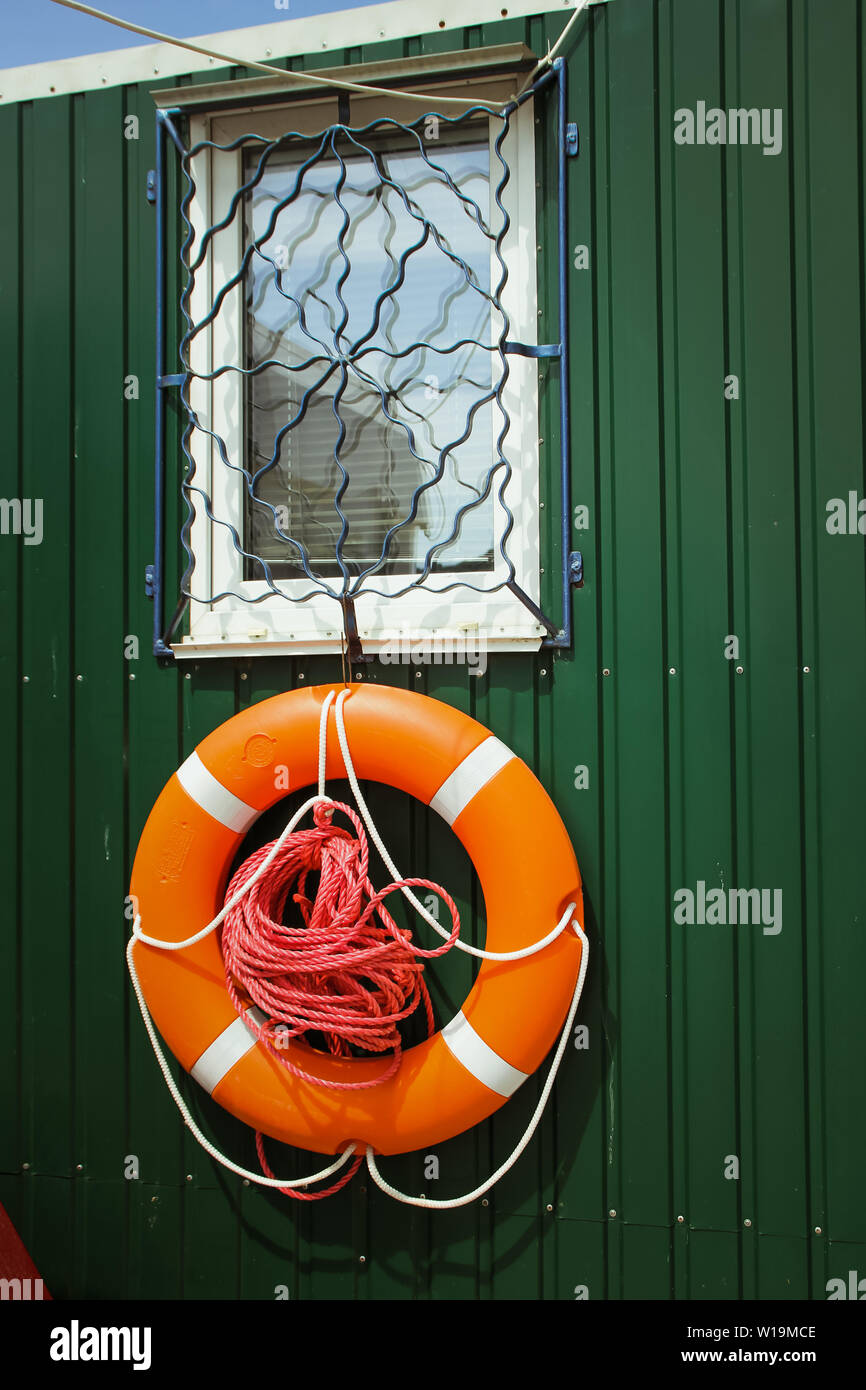 An orange life buoy on a green wooden wall. Stock Photo