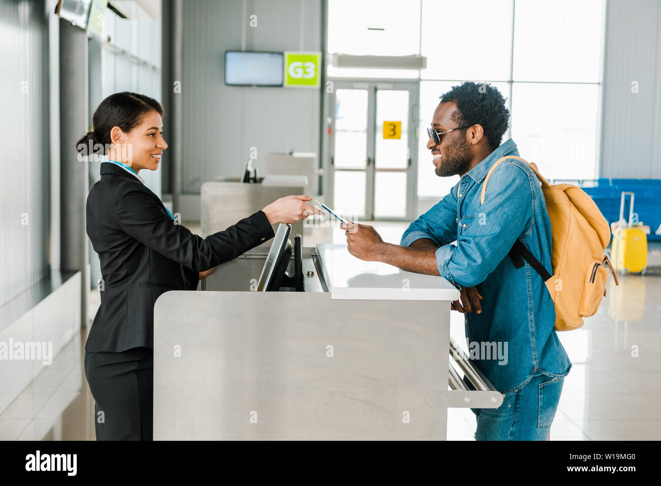 smiling african american airport worker taking passport and air ticket