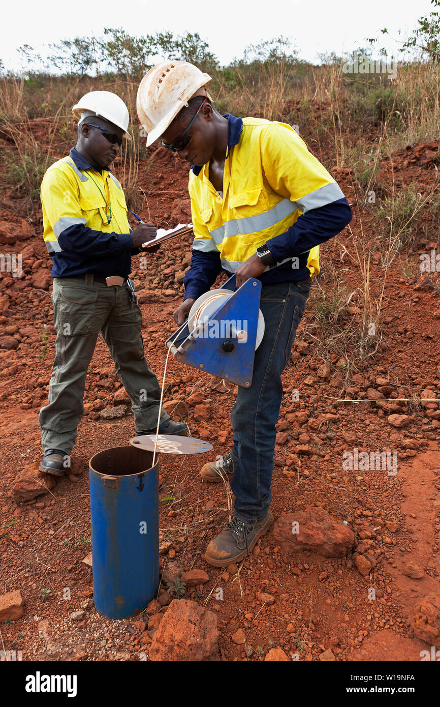 Mining operations for transporting and managing iron ore. Hydro geologists checking mine standing water level - measuring depth in borehole each week. Stock Photo