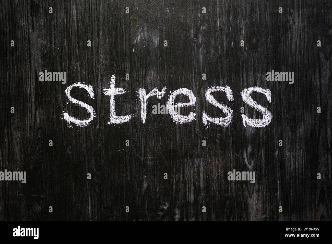 Stress word handwritten on black wood background. Sign, concept of