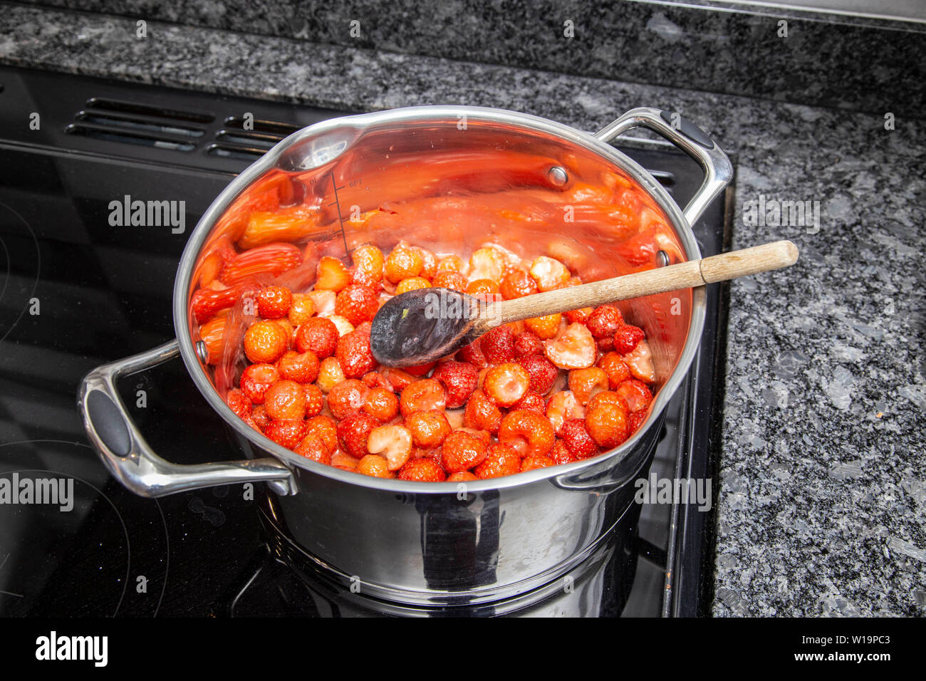 Heating strawberries uintil they are soft to make strawberry jam on an induction hob, stainless