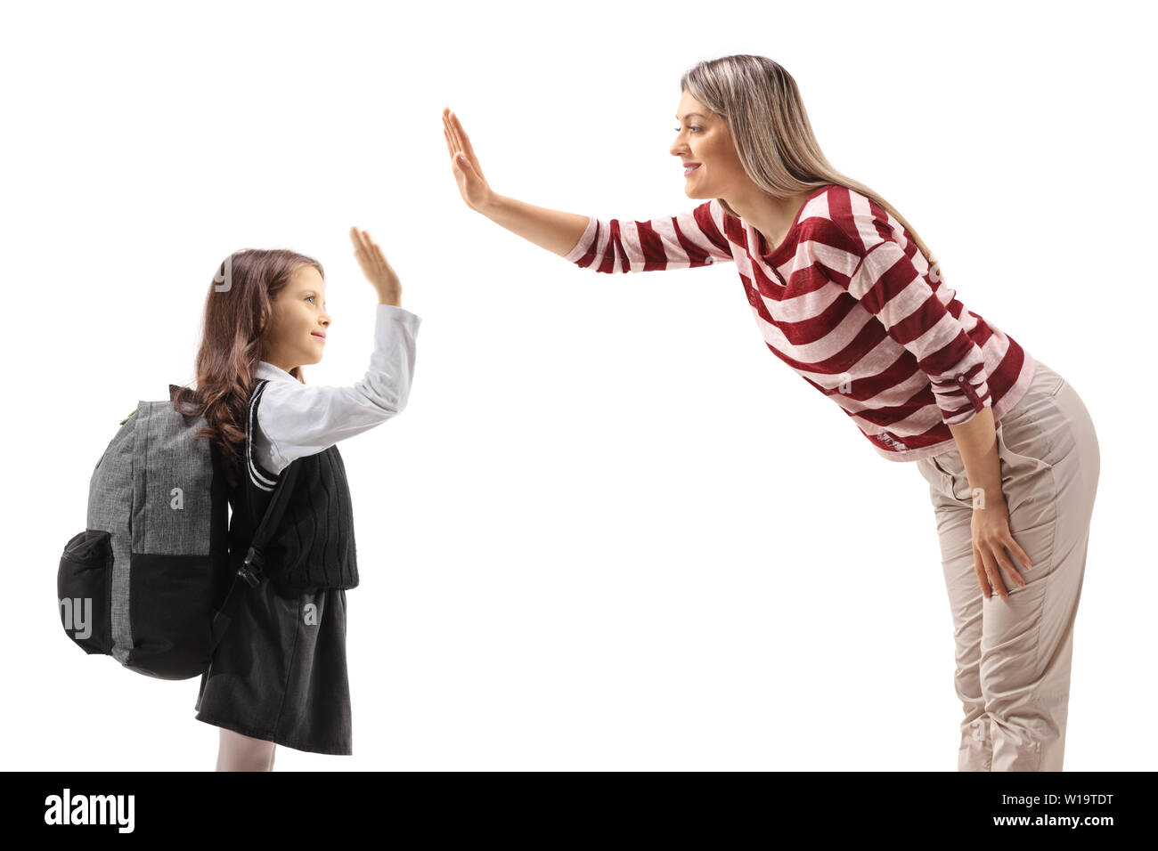 Schoolgirl high-fiving with a young woman isolated on white background Stock Photo