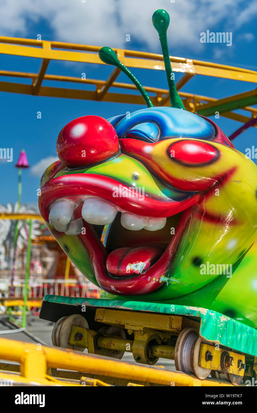 A colourful comic fairground rollercoaster carriage on the rails at a funfair in Southern England. Stock Photo