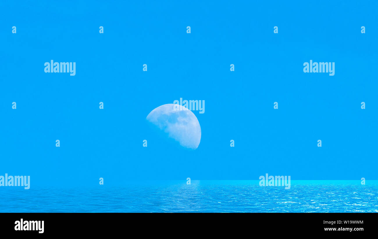 Moon over the blue wide sea with reflections Stock Photo