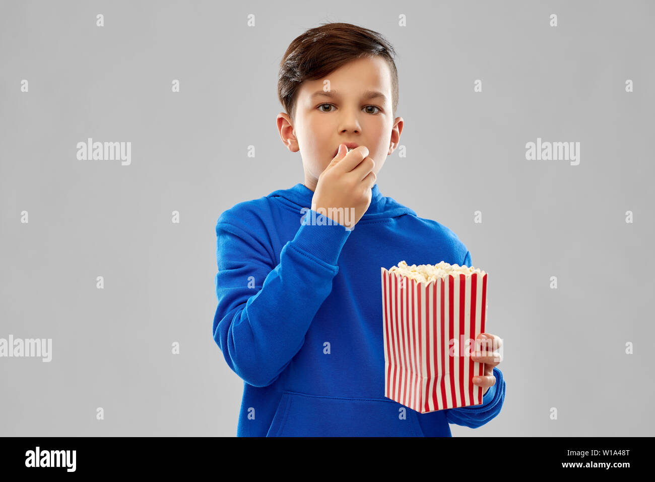 boy in blue hoodie eating popcorn Stock Photo Alamy