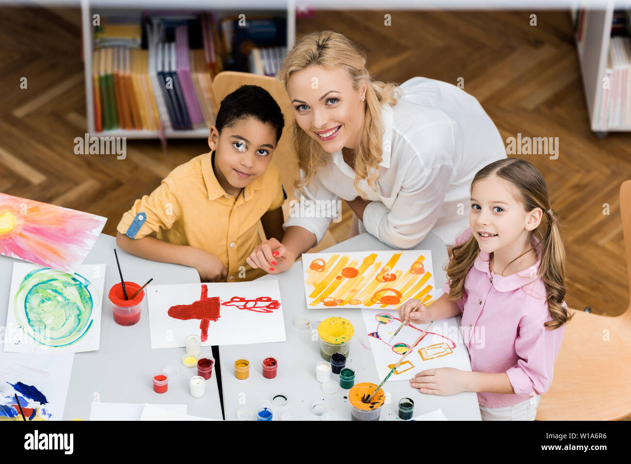 overhead view of cheerful teacher smiling with happy multicultural kids Stock Photo