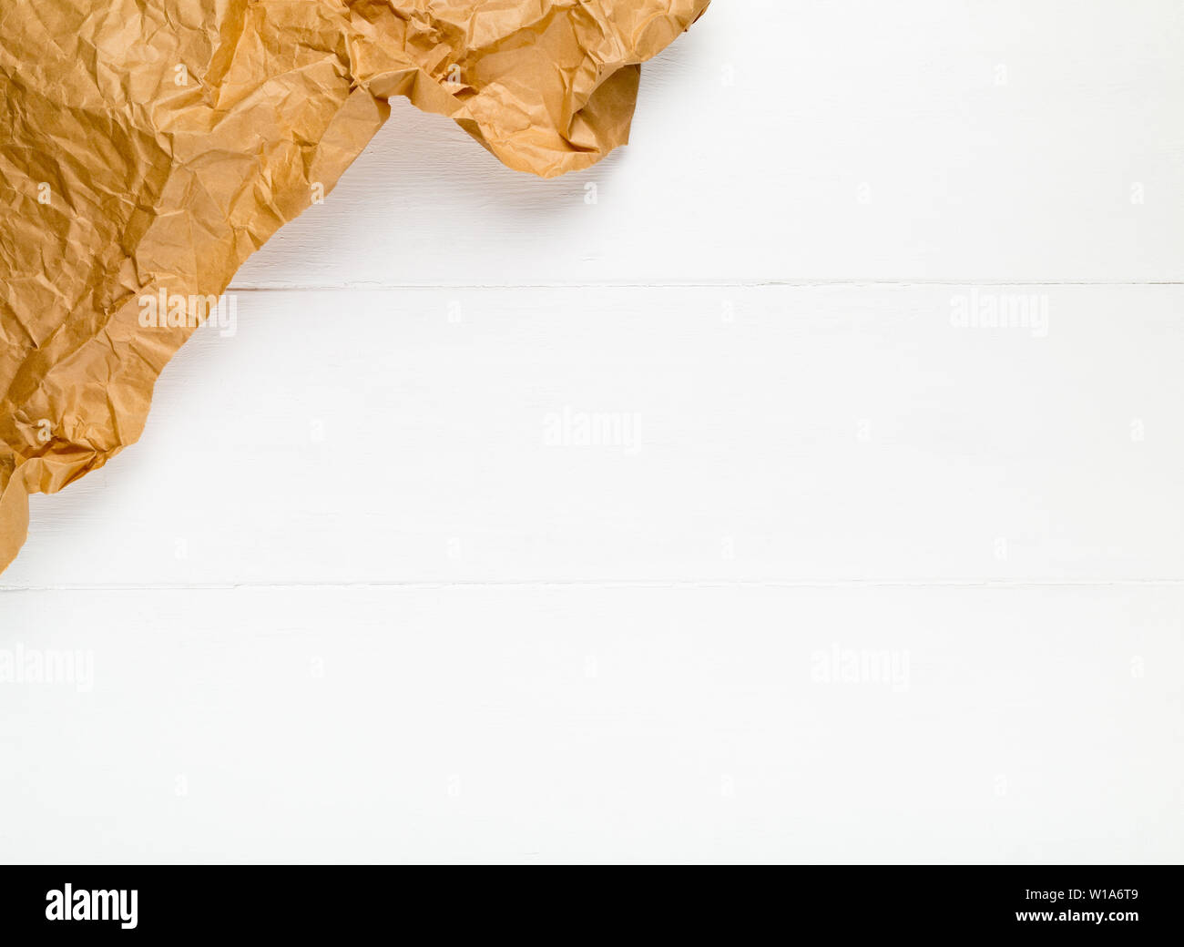Crumbled brown packing paper on white wooden kitchen table with copy space Stock Photo