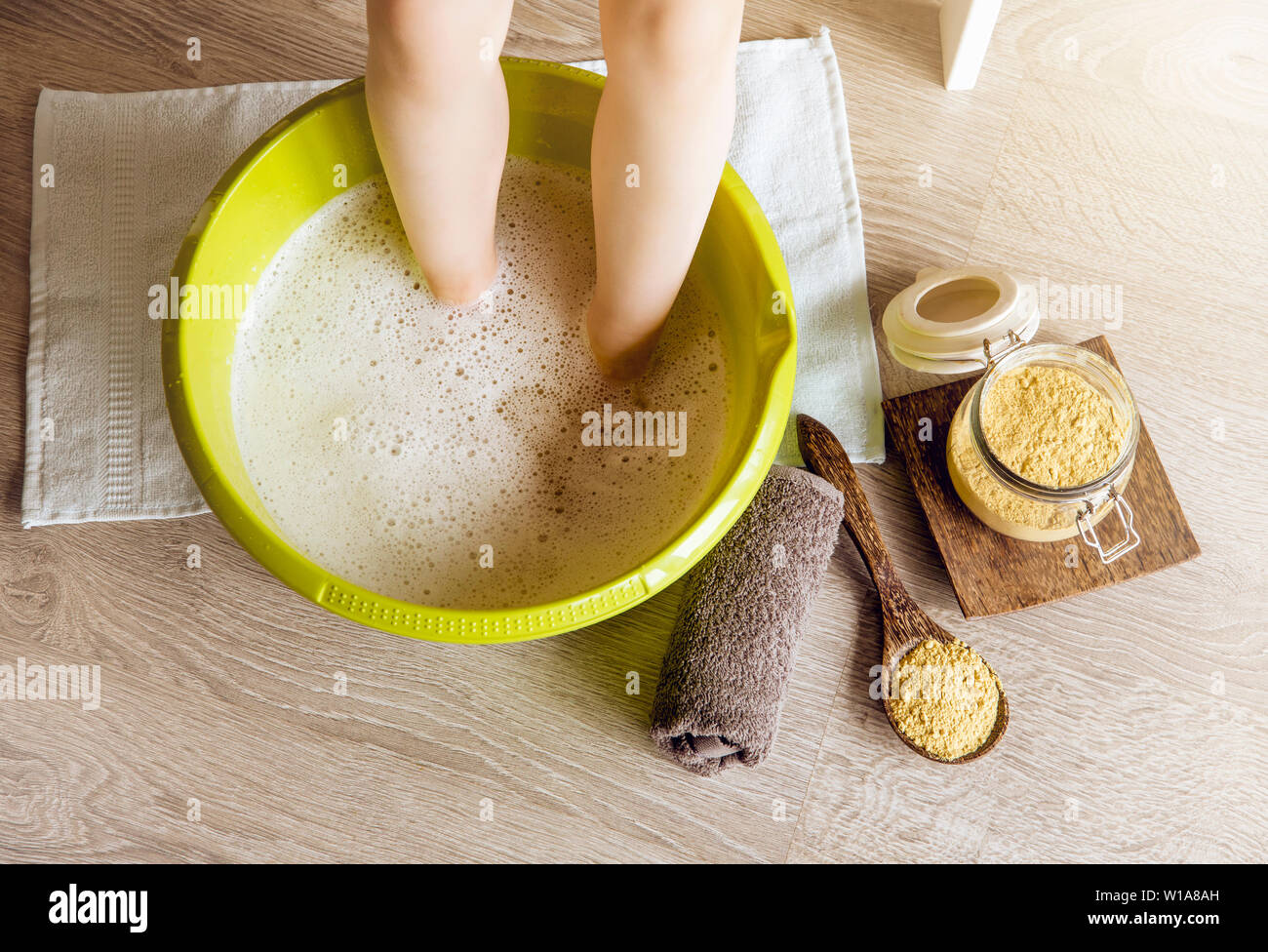 Child taking a healing warming foot bath with mustard powder, adding  mustard powder to foot bath with wooden spoon. Against cold illness, aches  and im Stock Photo - Alamy