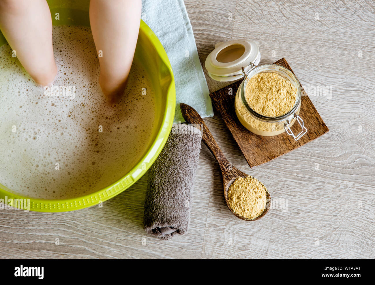 Child taking a healing warming foot bath with mustard powder, adding  mustard powder to foot bath with wooden spoon. Against cold illness, aches  and im Stock Photo - Alamy