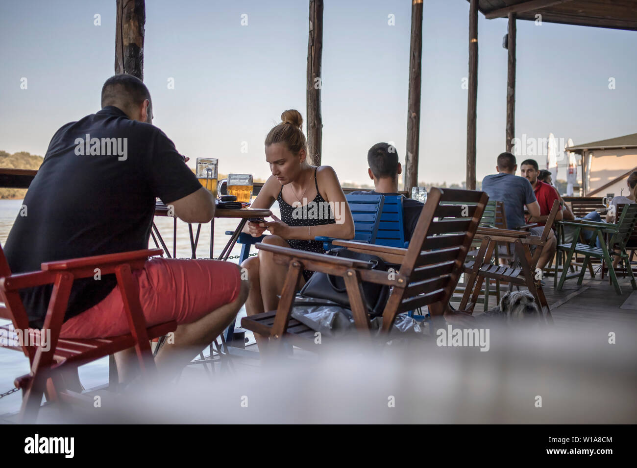Belgrade, Serbia, June 27th 2019: Urban scene with people sitting at a cafe terrace at Danube riverside promenade in Zemun Stock Photo