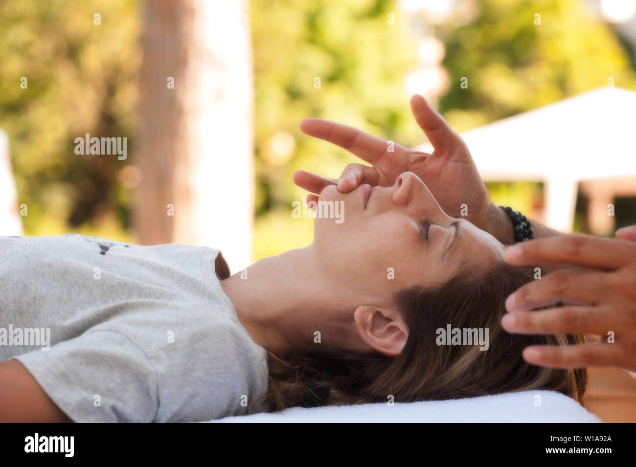 A young beautiful woman lying on the couch undergoes a regenerating facial massage Stock Photo