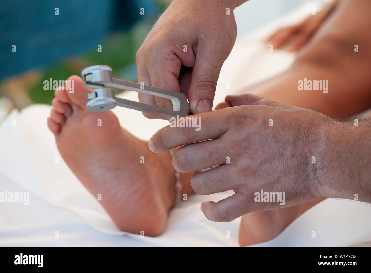 The massage therapist during a session of plantar reflexology with a tuning fork Stock Photo