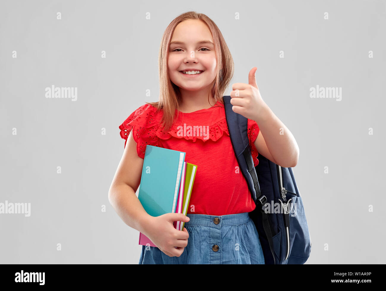 student girl with books and bag showing thumbs up Stock Photo - Alamy