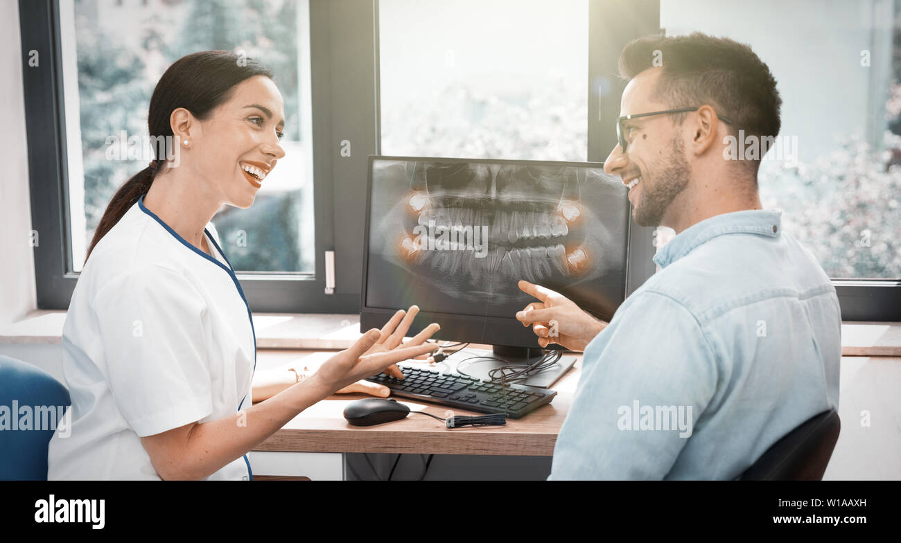 Dentist and patient choosing treatment in a consultation with x-ray image on screen Stock Photo