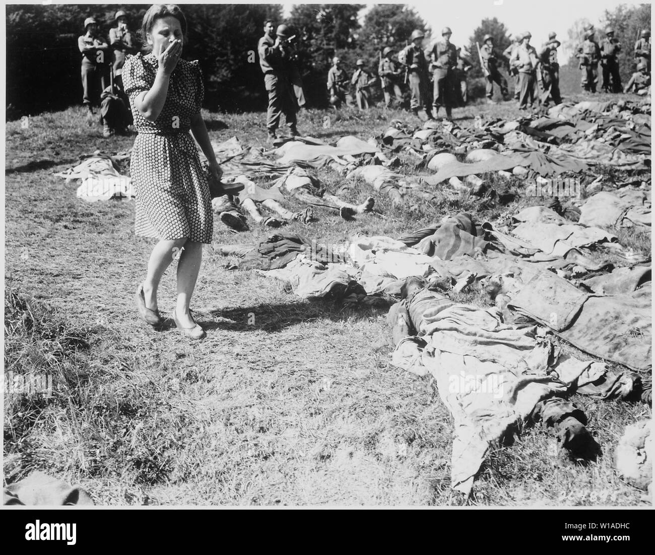 A German girl is overcome as she walks past the exhumed bodies of some of the 800 slave workers murdered by SS guards near Namering, Germany, and laid here so that townspeople may view the work of their Nazi leaders.; General notes:  Use War and Conflict Number 1124 when ordering a reproduction or requesting information about this image. Stock Photo