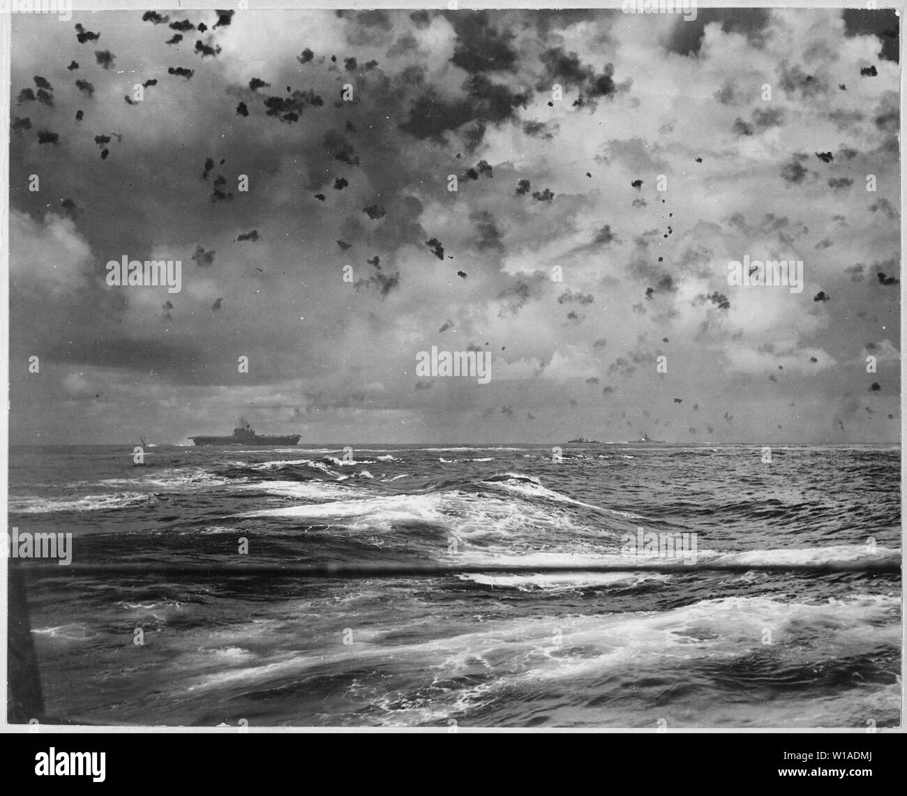 A Japanese bomb splashes astern of a U.S. carrier as the enemy plane pulls out of its dive above the carrier. In the center is another enemy plane that has made an unsuccessful dive. Battle of Santa Cruz.; General notes:  Use War and Conflict Number 977 when ordering a reproduction or requesting information about this image. Stock Photo