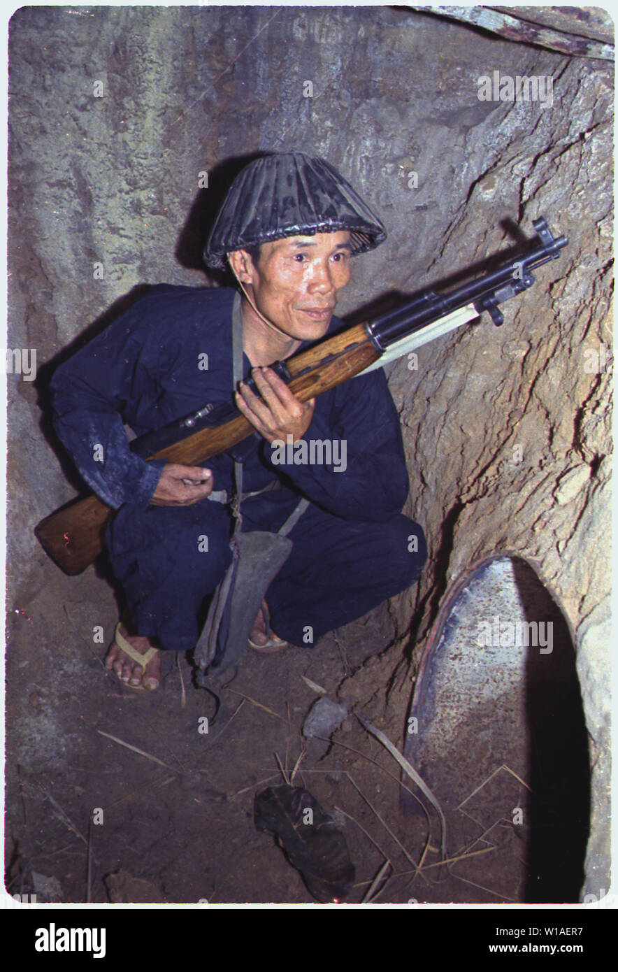 A Viet Cong soldier crouches in a bunker with an SKS rifle. Stock Photo