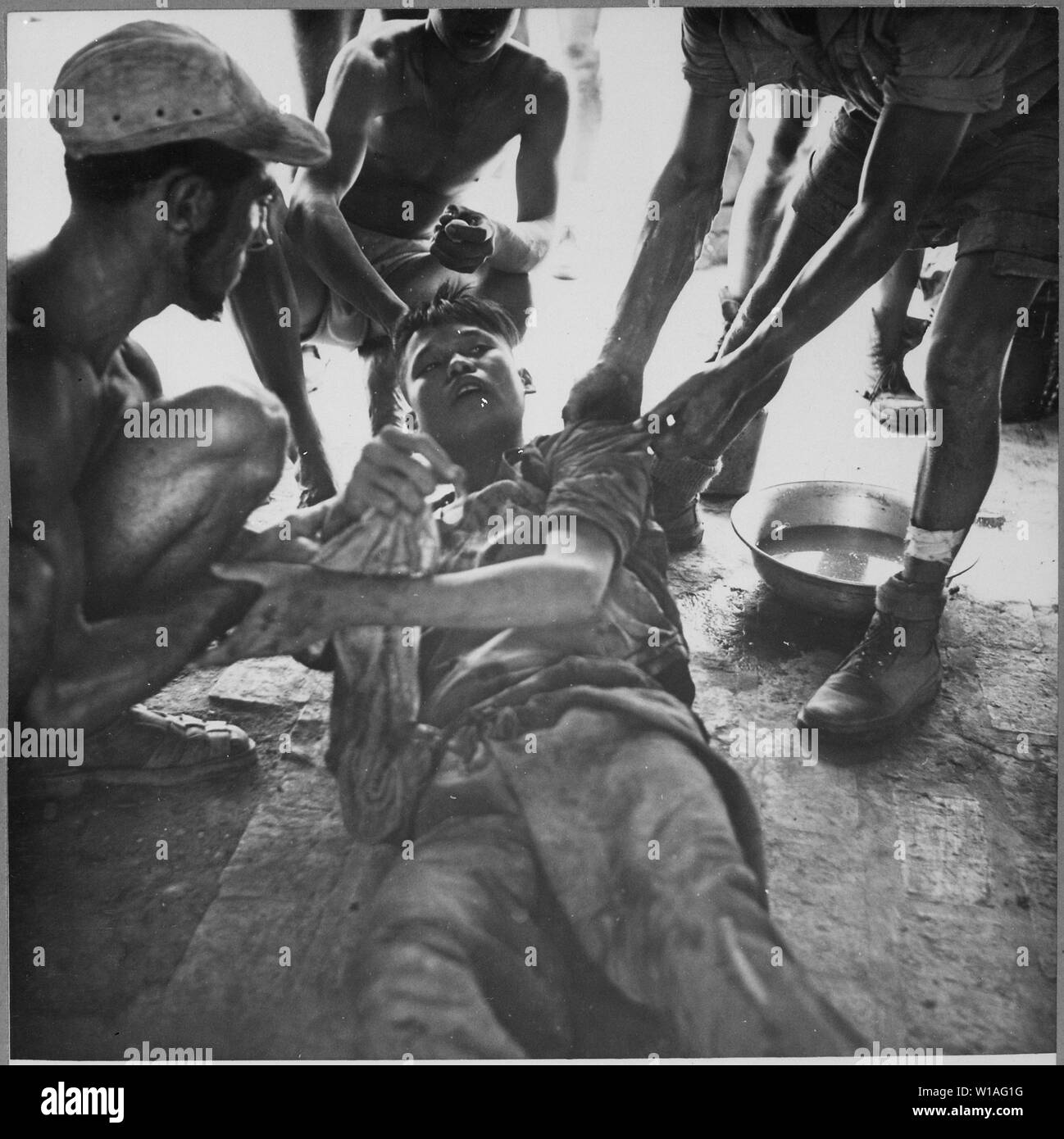 A wounded Vietminh prisoner is given first aid by Franco Vietnamese medicals after hot fire fight near Hung Yen, south of Hanoi., ca. 1954; General notes:  Use War and Conflict Number 384 when ordering a reproduction or requesting information about this image. Stock Photo