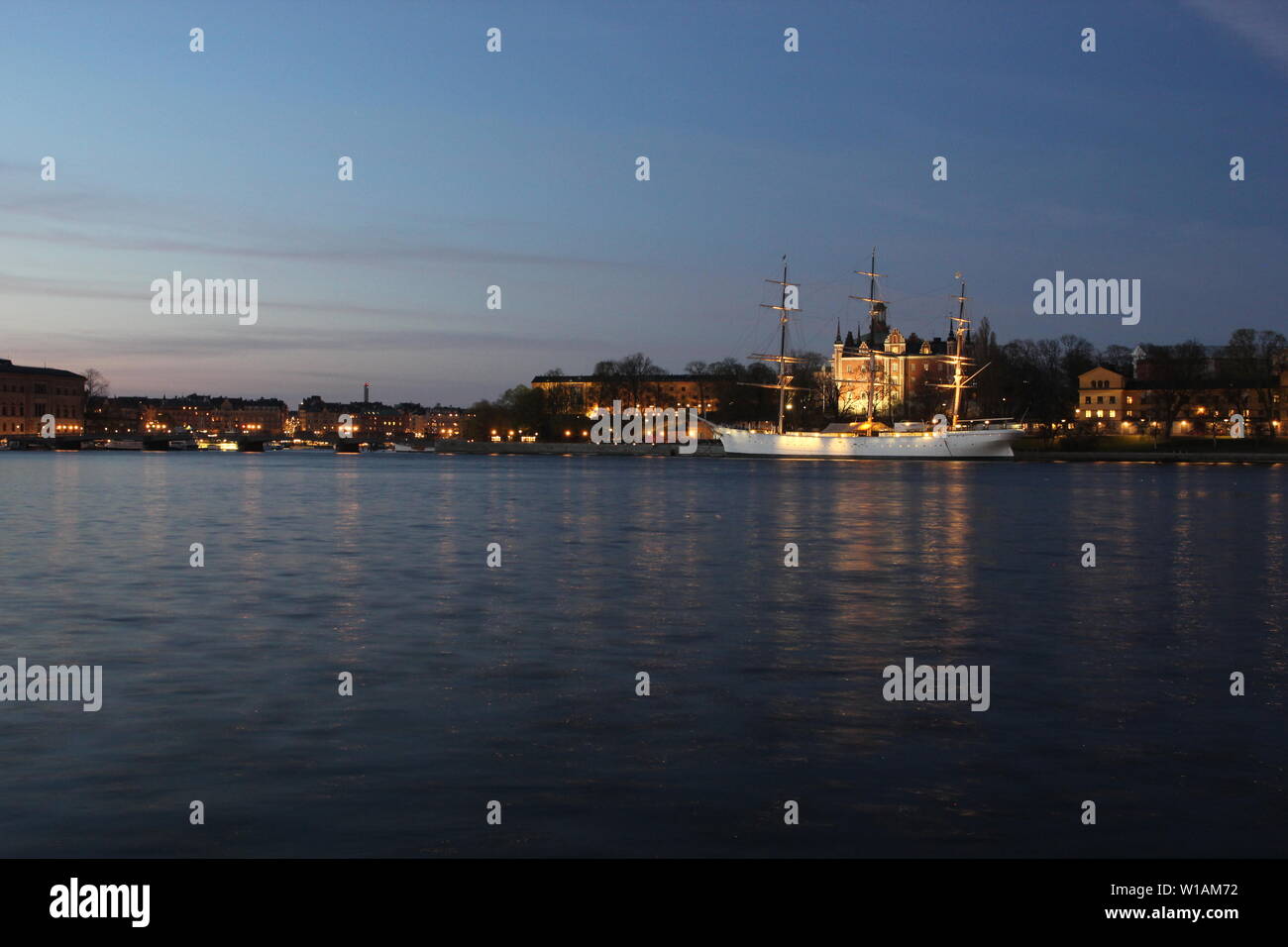 Cityscape views of Stockholm at dusk from the island of Gamla Stan with an old ship in the distance. Stock Photo