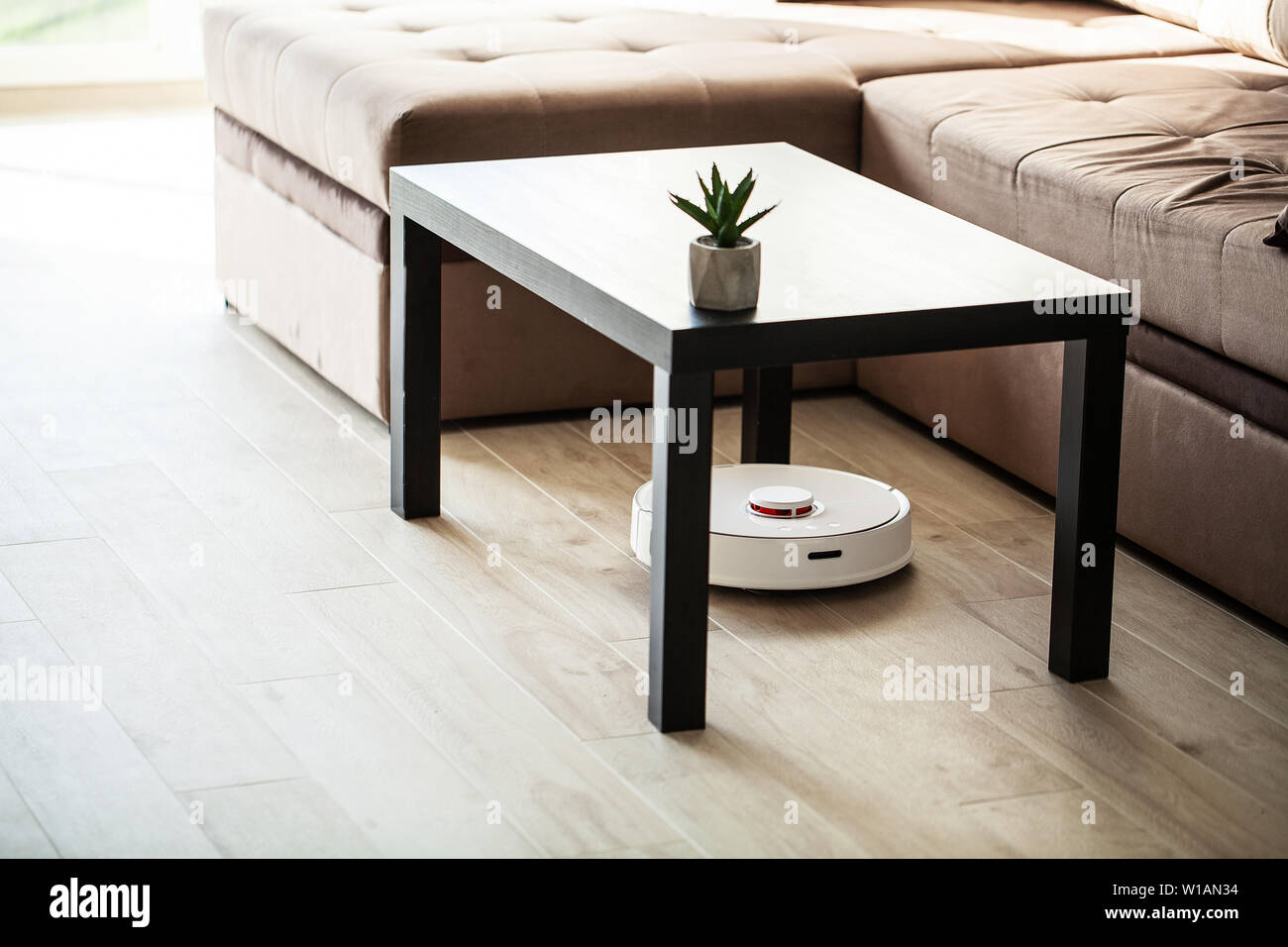 Smart House. Vacuum cleaner robot runs on wood floor in a living room ...