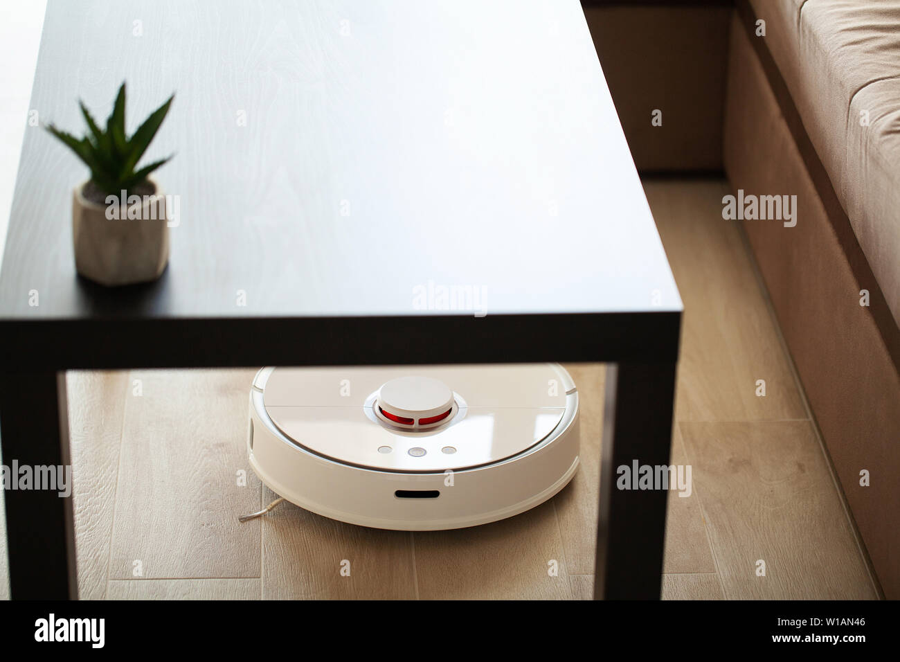 Smart House. Vacuum cleaner robot runs on wood floor in a living room ...
