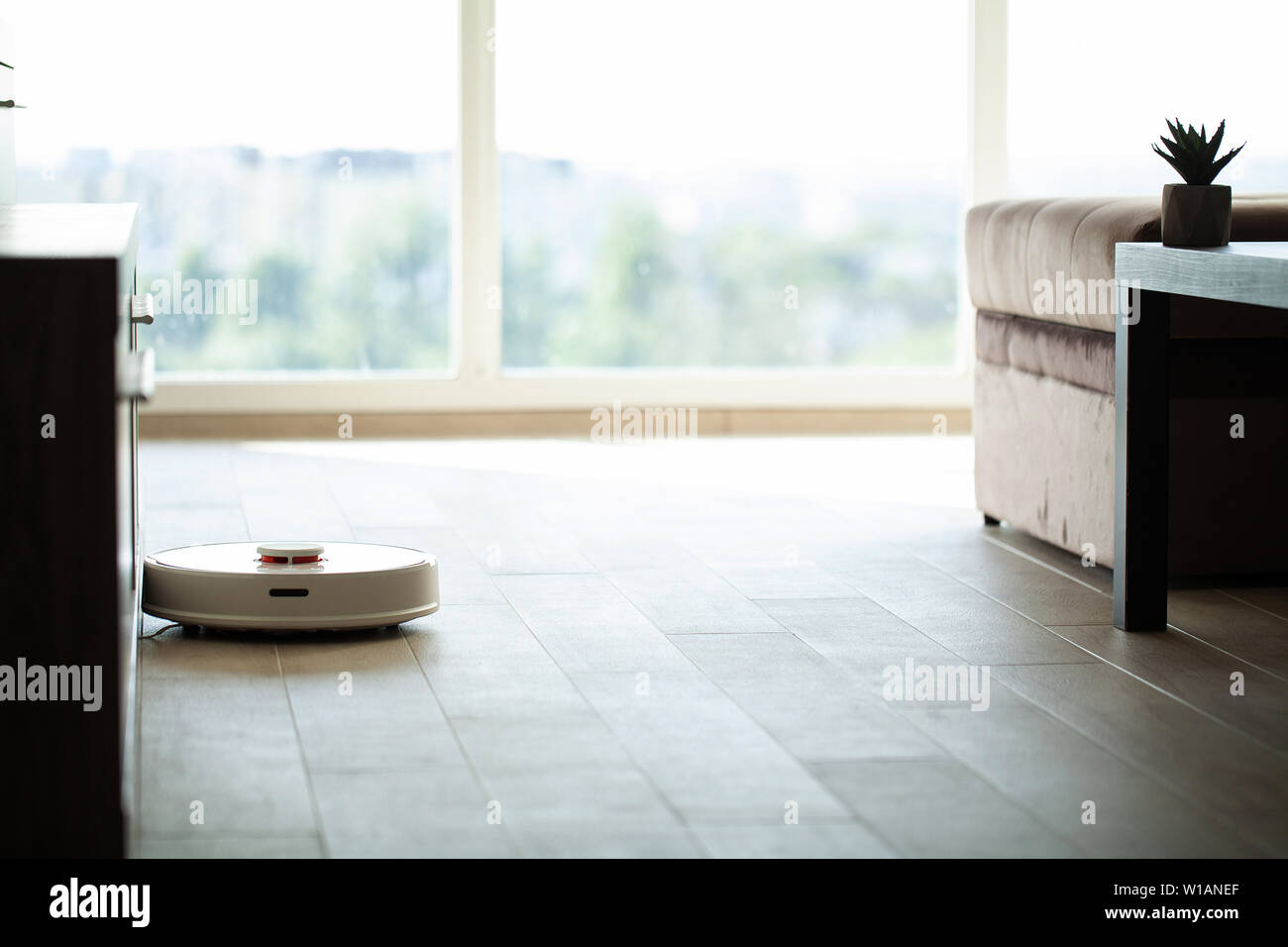 Smart House. Vacuum cleaner robot runs on wood floor in a living room ...