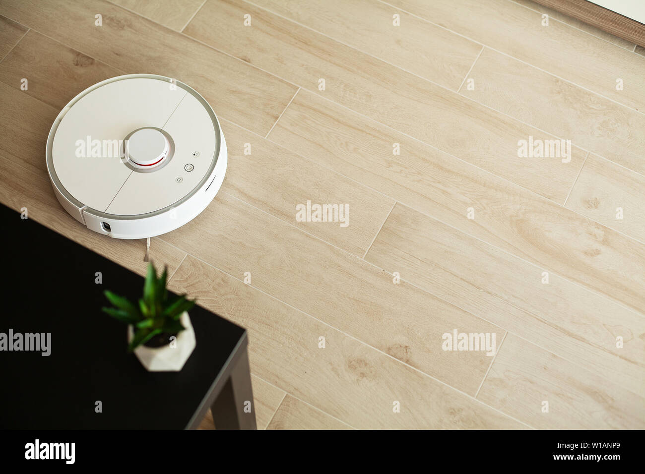 Smart House. Vacuum cleaner robot runs on wood floor in a living room ...