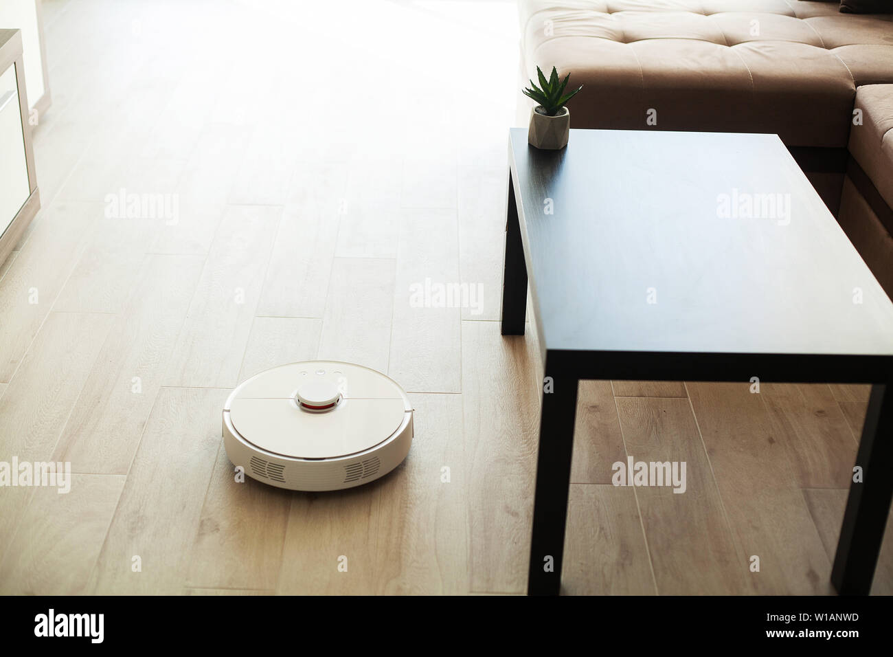 Smart House. Vacuum cleaner robot runs on wood floor in a living room ...